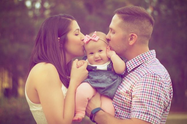 Parents kissing their baby girl, highlighting family love and connection, relevant to child custody discussions in Virginia.