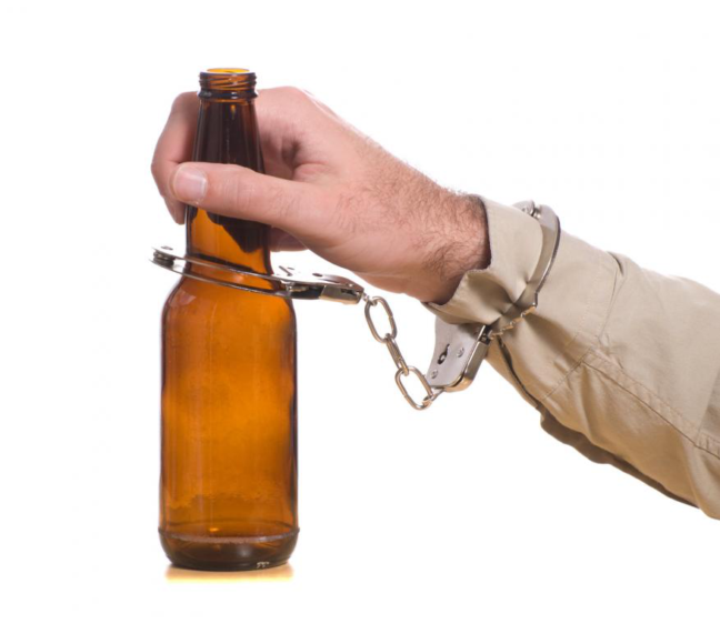 Hand holding a beer bottle secured with handcuffs, symbolizing DUI implications and legal consequences in Virginia.