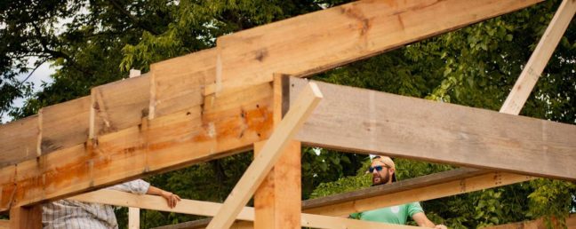 Construction workers collaborating on a wooden frame structure outdoors, highlighting contractor work relevant to claims against contractors in Virginia.