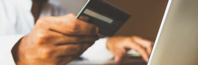 Person holding a credit card while using a laptop, illustrating online payment processes related to legal services.