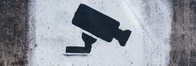 Black security camera icon on a textured white background, symbolizing surveillance and protection against contractor theft and fraud.