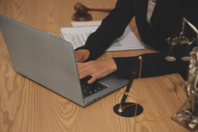 Lawyer typing on laptop at desk with legal documents, gavel, and scales of justice, emphasizing expertise in DUI defense at Coastal Virginia Law Firm.