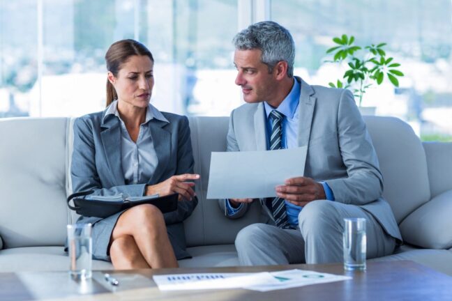 Professional couple discussing legal documents in a modern office setting, reflecting the supportive legal services offered for same-sex divorce in Virginia.