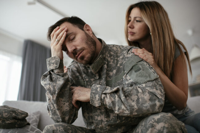 Military couple discussing emotional challenges during divorce, with the man in military uniform showing distress and the woman offering support.